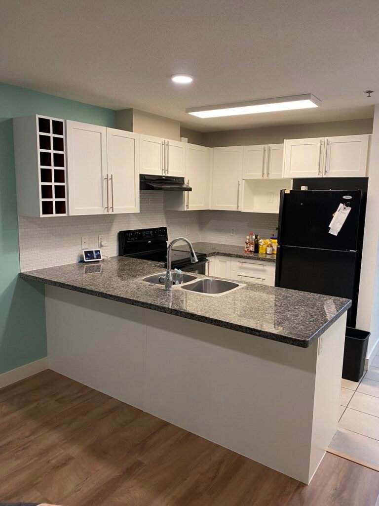 Same Kelowna kitchen after cabinet painting, cabinets now bright white