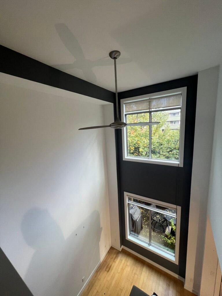 Lofted-ceiling condo after interior painting with white walls and a dark accent wall