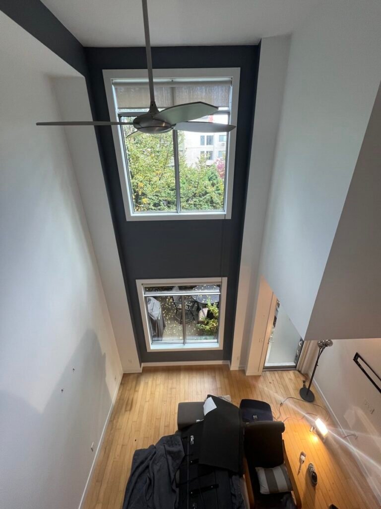 Lofted-ceiling condo after interior painting with white walls and a dark accent wall
